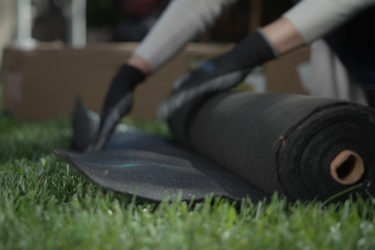 A person laying a landscape fabric