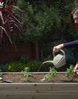 A woman watering her plants in Ecogardener elevated raised bed