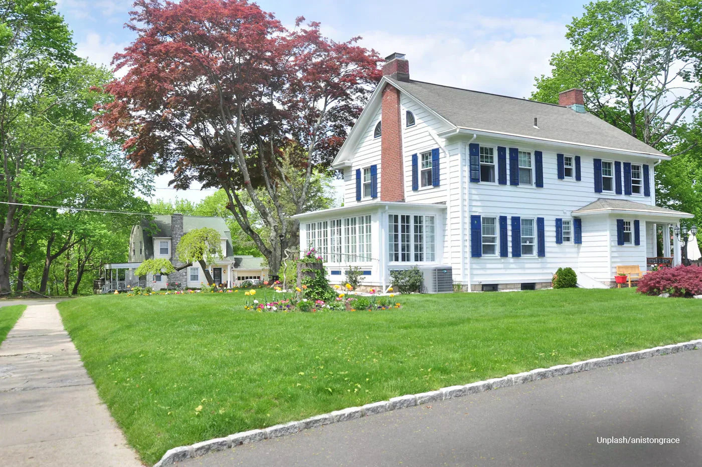Residential property with a lush, evenly cut lawn, clean edging, and landscaped flower beds, demonstrating healthy grass and proper lawn care.