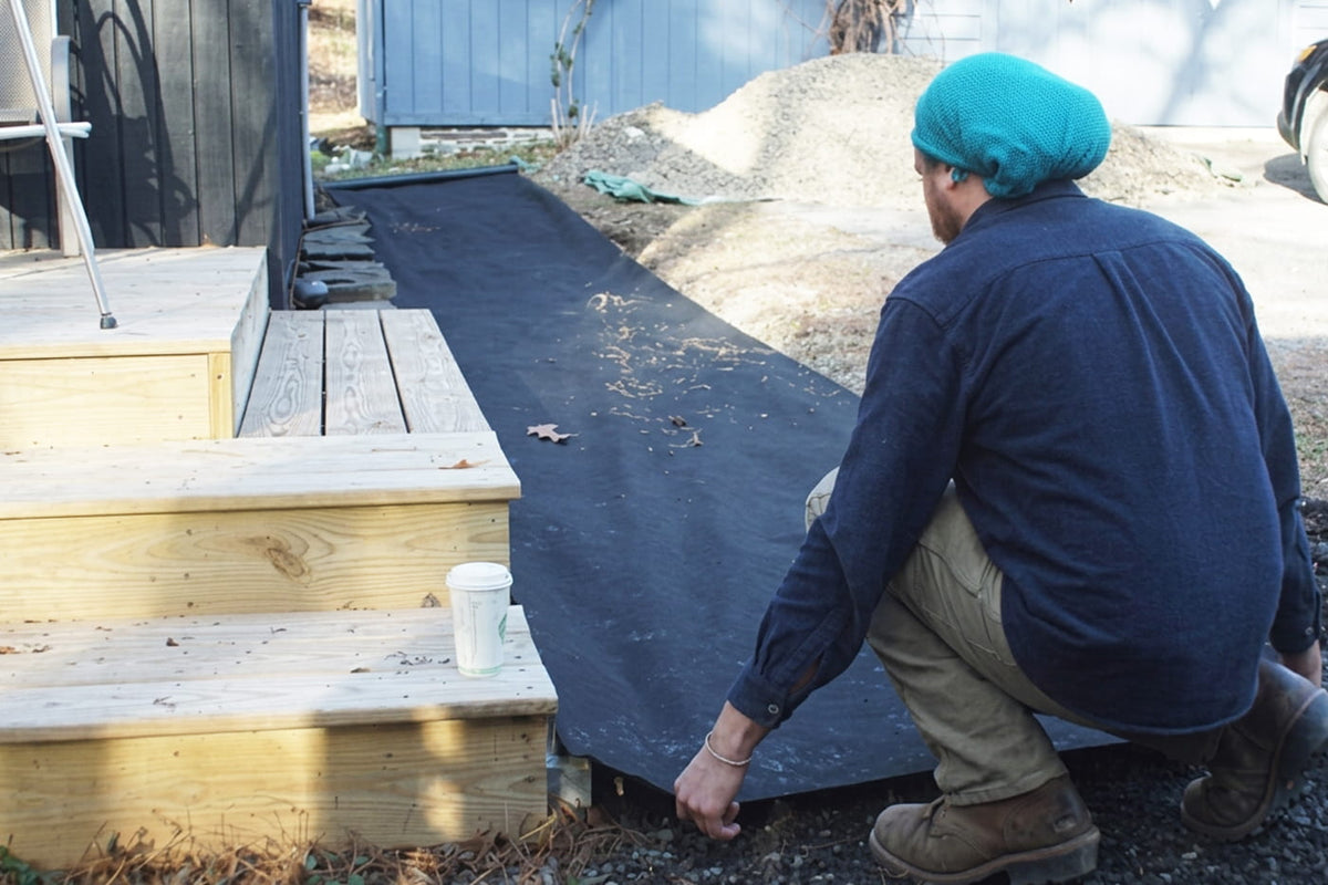 man laying landscape fabric