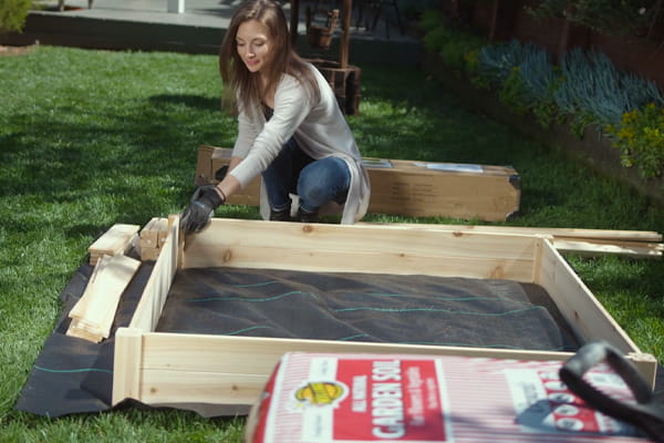 women installing raised bed with landscape at the bottom 