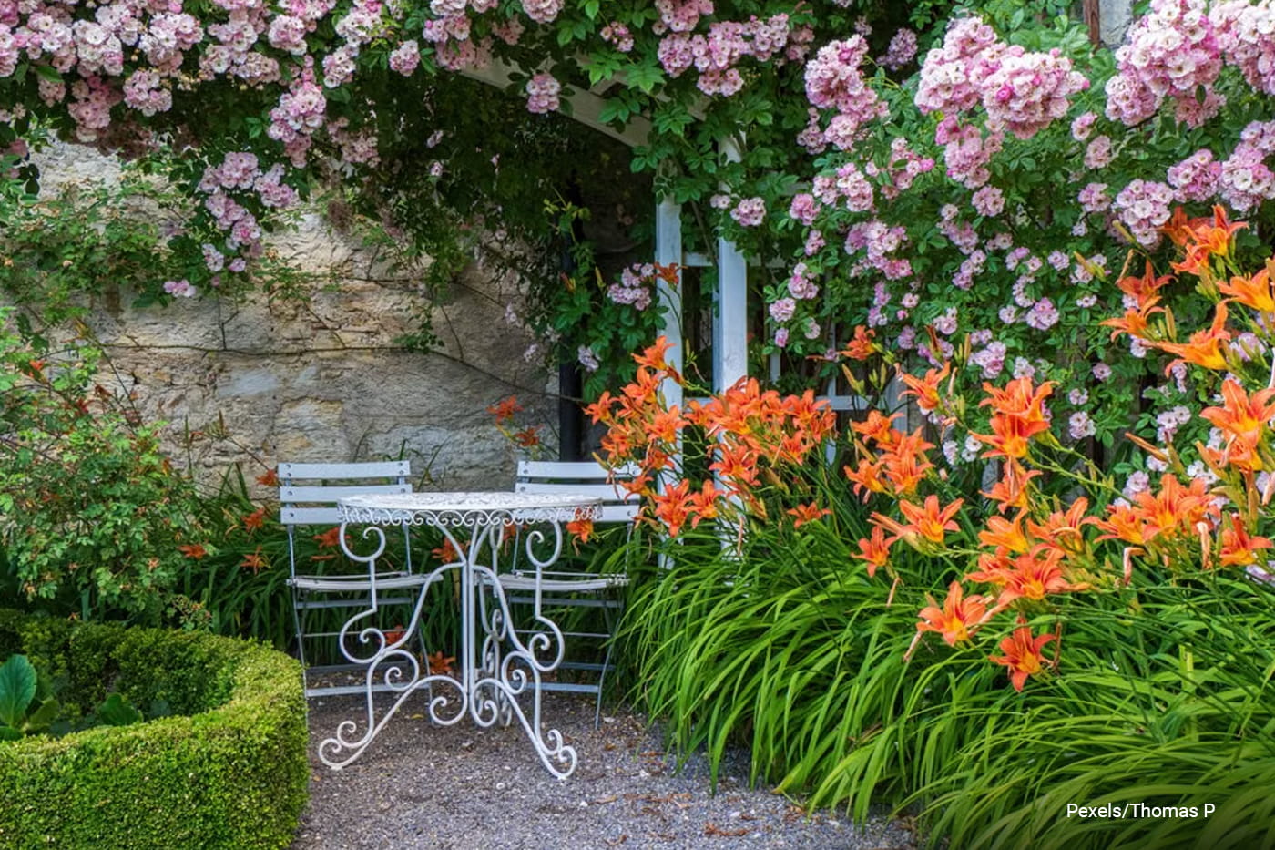 Enchanting garden setting with vibrant flowers and a classic wrought-iron table and chairs.