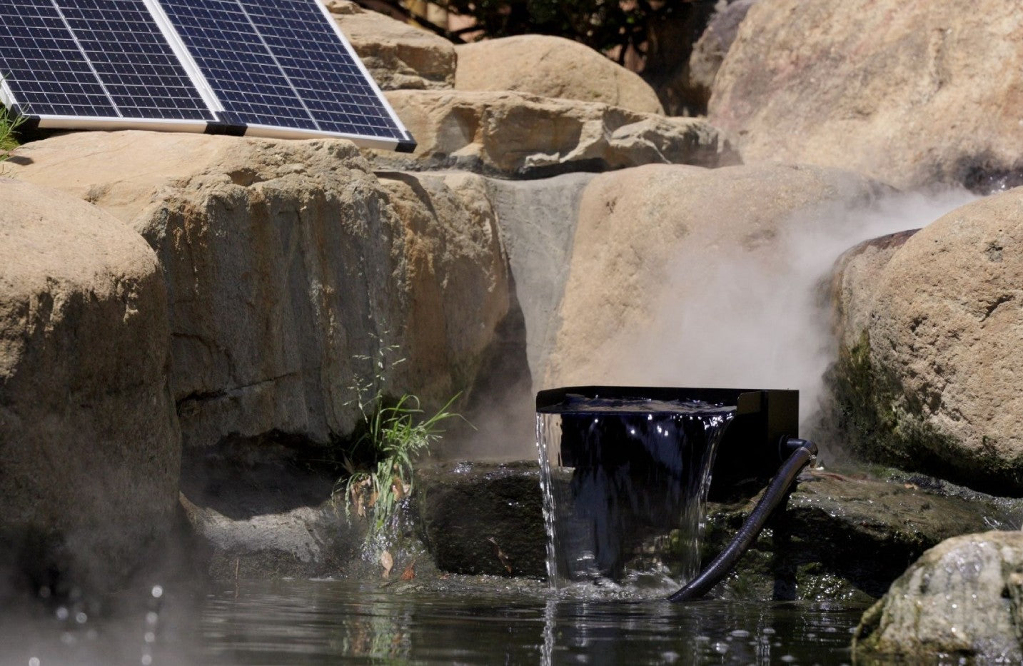 A solar waterfall in a pond and above it is its solar panel