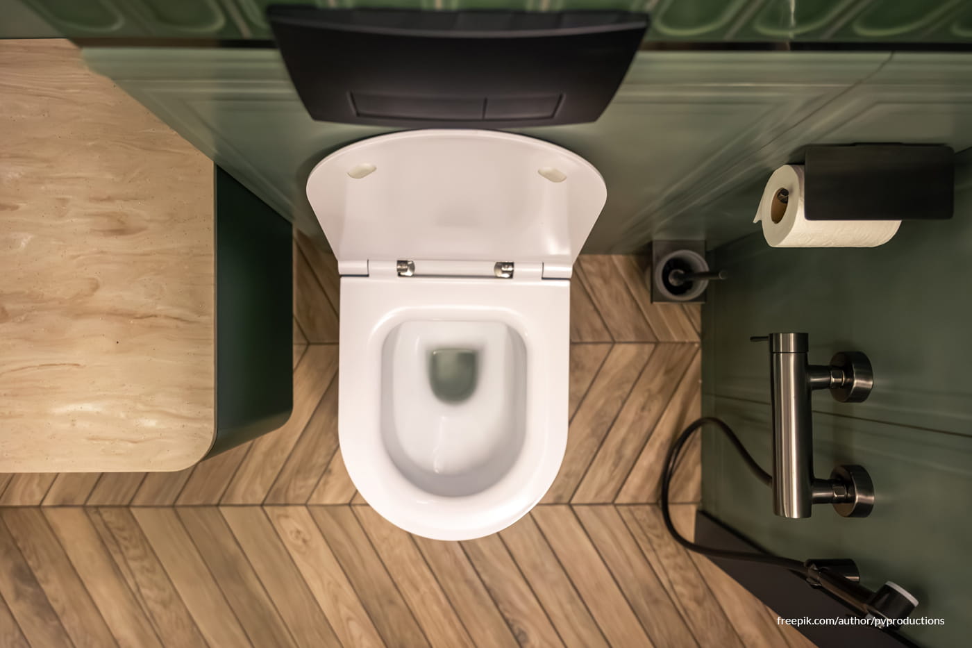 White toilet in a bathroom with wooden floor and green walls