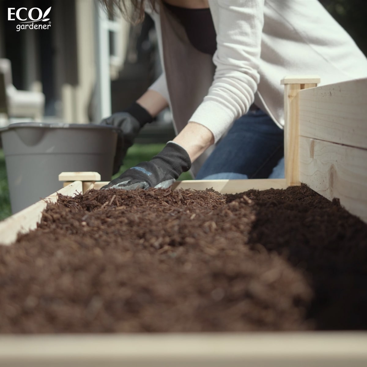 A woman putting soil in the Ecogardener tiered raised bed planter